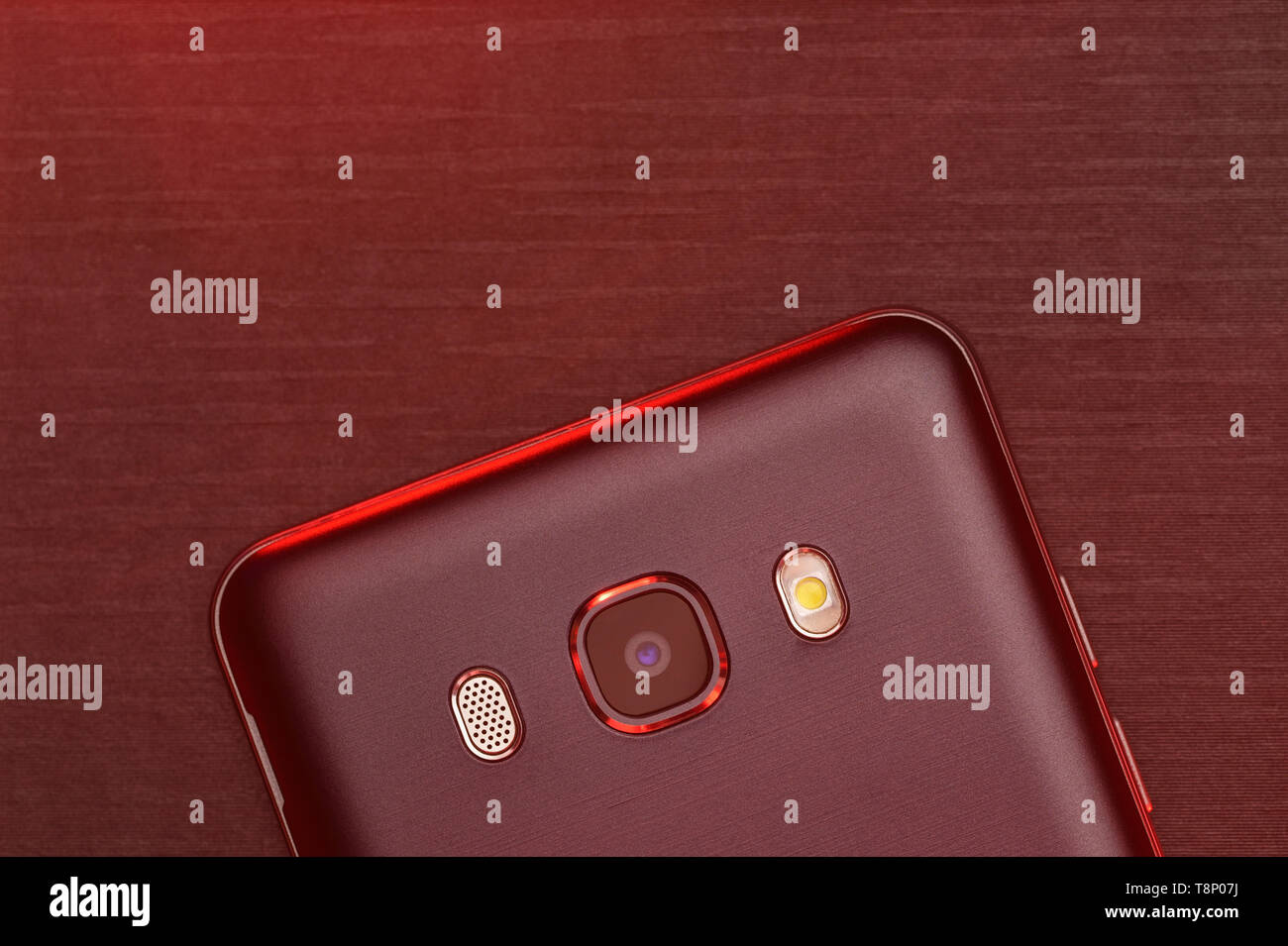 Ein Fragment der Cell Phone Case in Schwarz mit roter Hintergrundbeleuchtung. Das Telefon liegt auf dem Schwarzen technologische gerippte Oberfläche der Kamera mit roten zurück Stockfoto