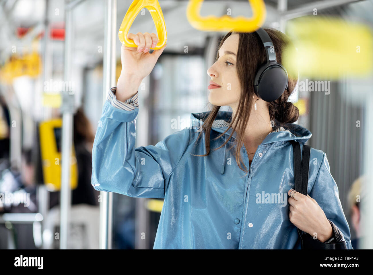 Junge stilvolle Frau genießen Reise in den öffentlichen Verkehrsmitteln, mit Kopfhörer, während in der modernen Straßenbahn verschieben Stockfoto