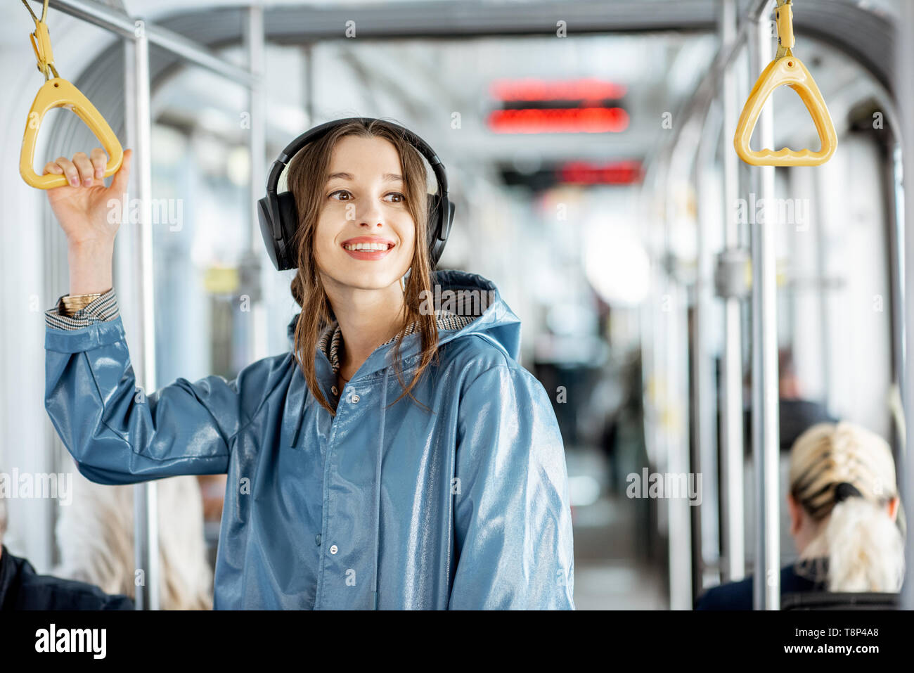 Junge stilvolle Frau genießen Reise in den öffentlichen Verkehrsmitteln, mit Kopfhörer, während in der modernen Straßenbahn verschieben Stockfoto