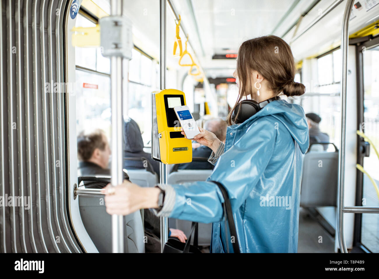 Frau Zahlung conctactless mit Smartphone für die öffentlichen Verkehrsmittel in der Straßenbahn Stockfoto