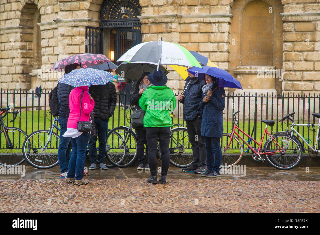 Eine Gruppe von Touristen mit bunten Regenschirmen im Regen am Radcliffe Square, Oxford by the Radcliffe Camera Stockfoto