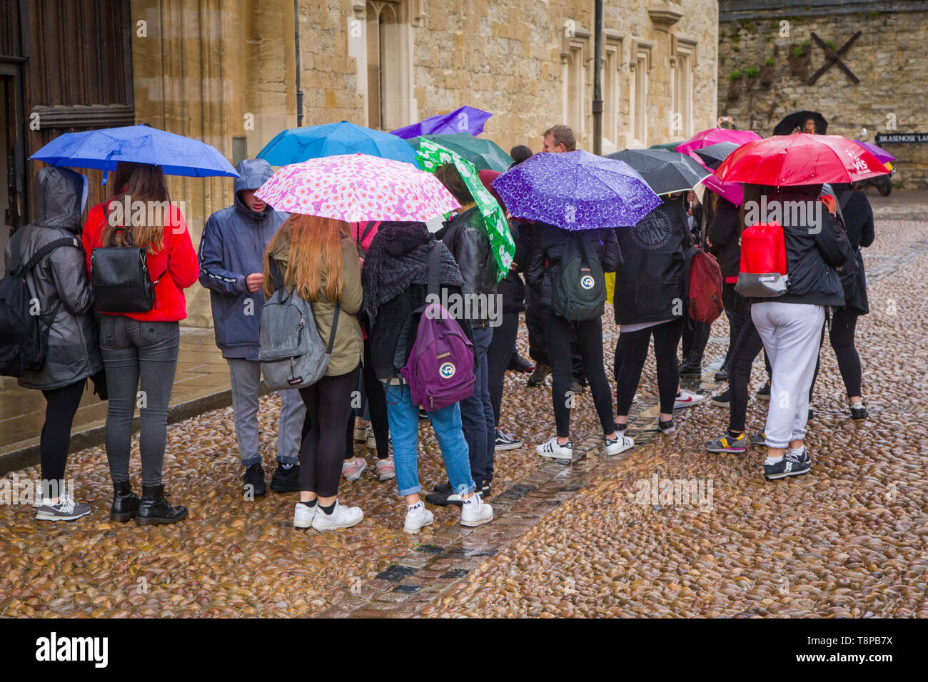 Eine Gruppe von Schülerinnen und Schülern mit Sonnenschirmen im Regen in Oxford Stockfoto