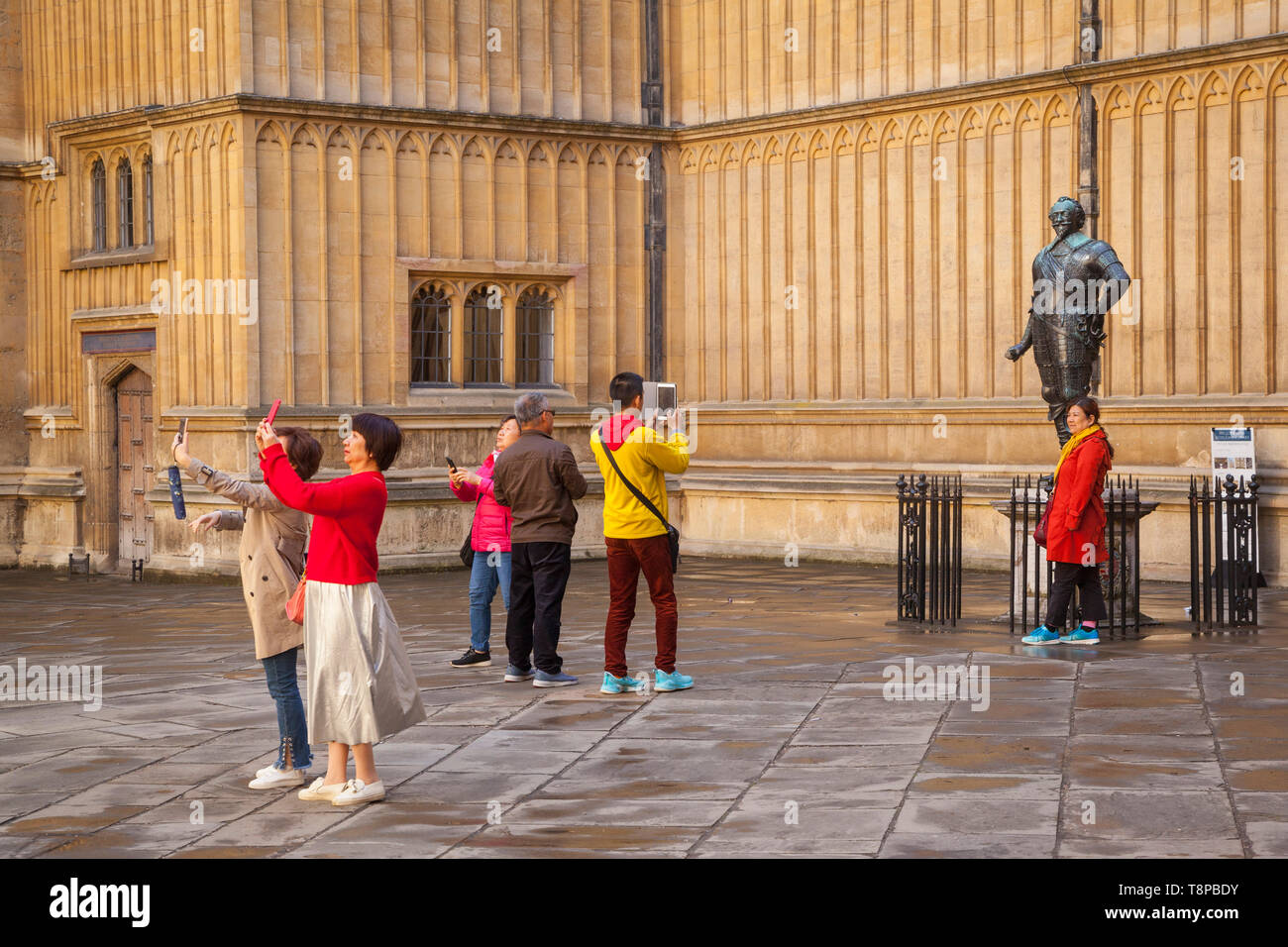 Chinesische Touristen fotografieren auf ihren Handys in der Alten Schule Quad außerhalb der Bodleian Library, Oxford Stockfoto