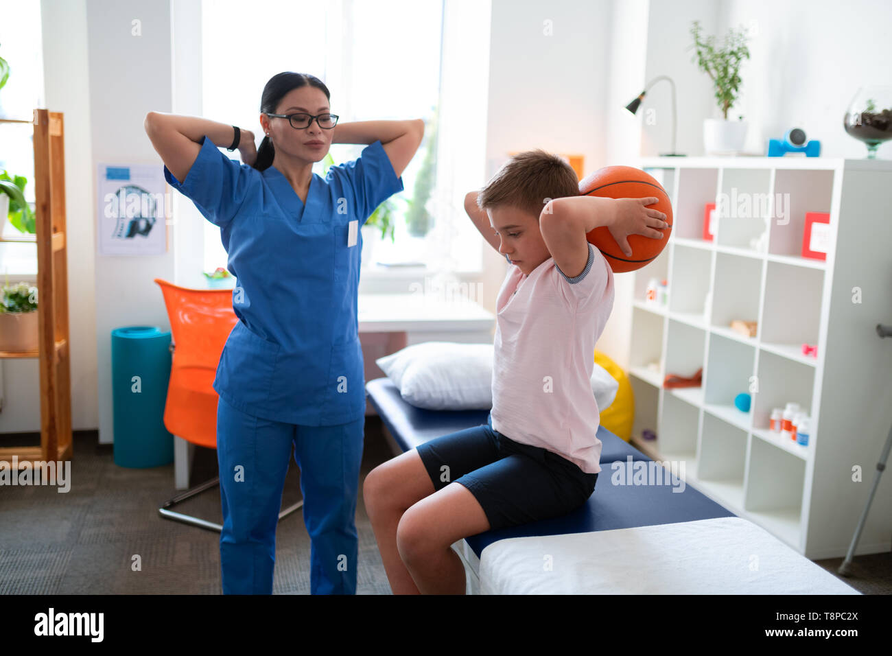 Schweren asiatischen Arzt in der blauen Uniform Prüfung Zustand ihrer Patienten Stockfoto