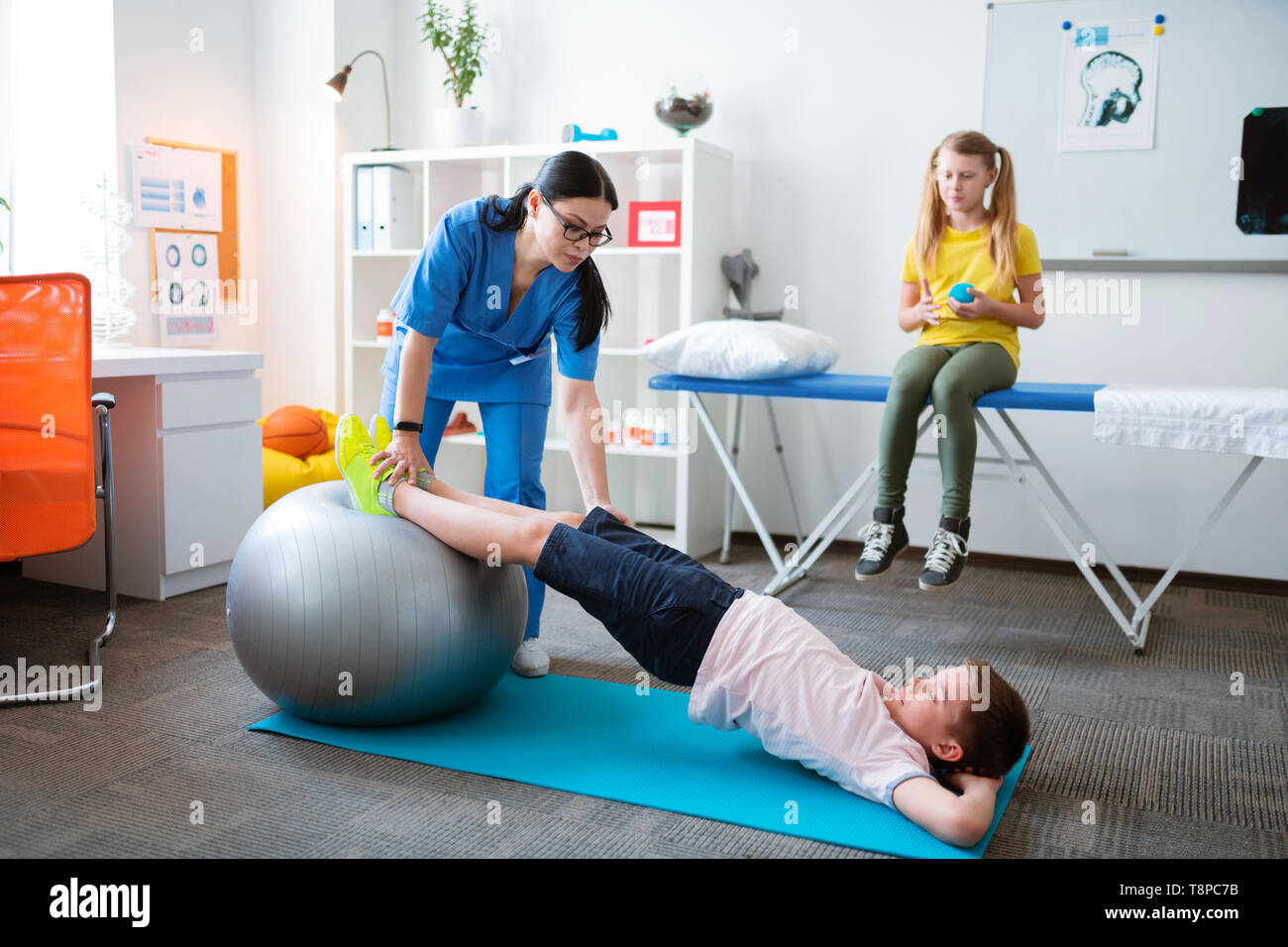 Aktive kleine Patient stretching ganze Körper, während lehnte sich auf Pilates Ball Stockfoto