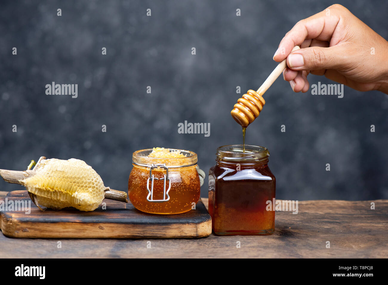 Hand Holz- Honig Pendelarm, Löffel Honig auf ein Glas Tee auf Holz Tisch Stockfoto