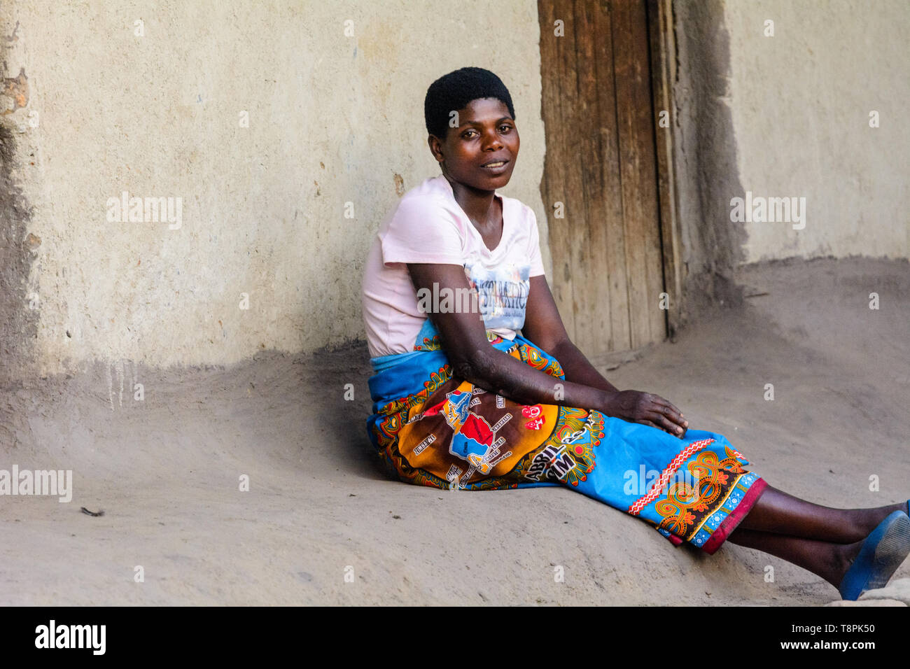 Junge malawische Frau sitzt auf der Stufe Ihrer Schlamm Haus in einem Dorf in Malawi Stockfoto