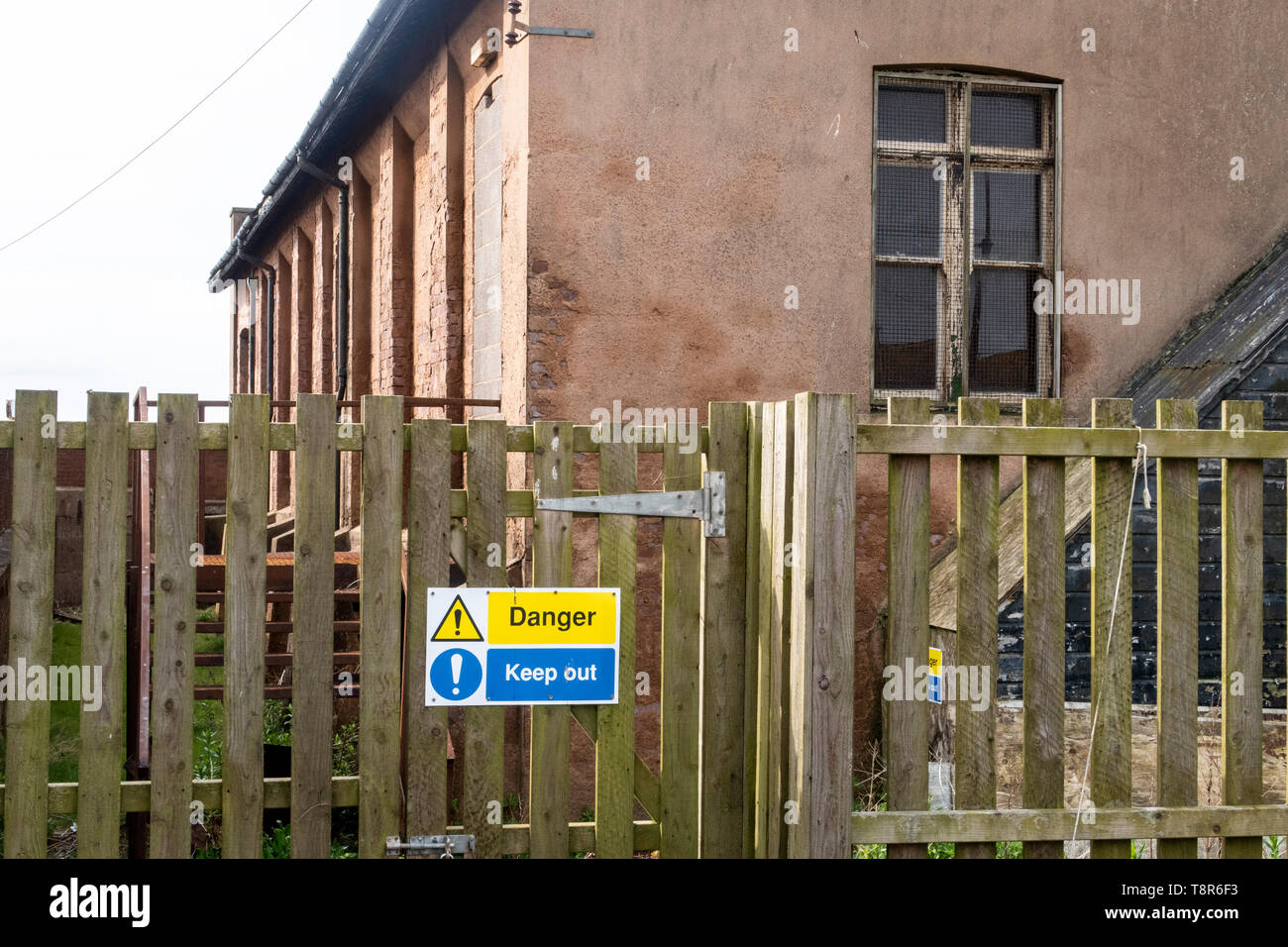 Gefahr, behalten Sie sich abmelden Hinweis außerhalb eines zerfallenden Gebäude, der Drill Hall in Honiton, Devon, Großbritannien Stockfoto