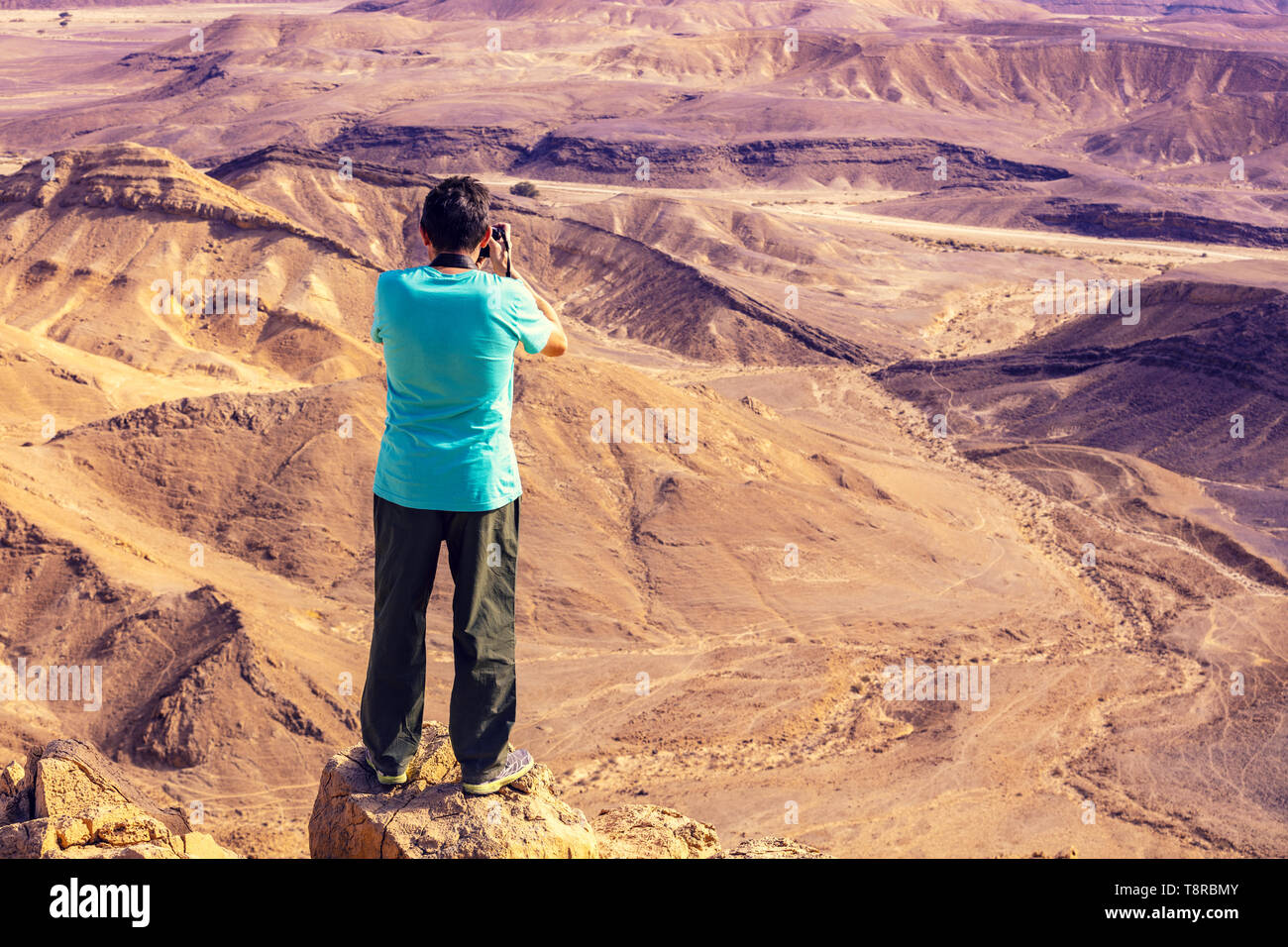 Ein Mann stand auf dem Rand der Klippe in der Wüste und ein Foto Stockfoto