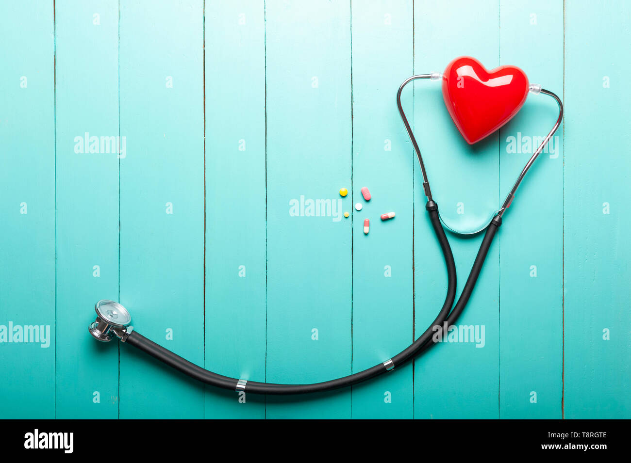 Ansicht von oben Stethoskope, rote Herzen Modell und Drogen auf grünen Schreibtisch aus Holz, Klinik Schreibtisch, medizinischen und gesundes Konzept. Stockfoto