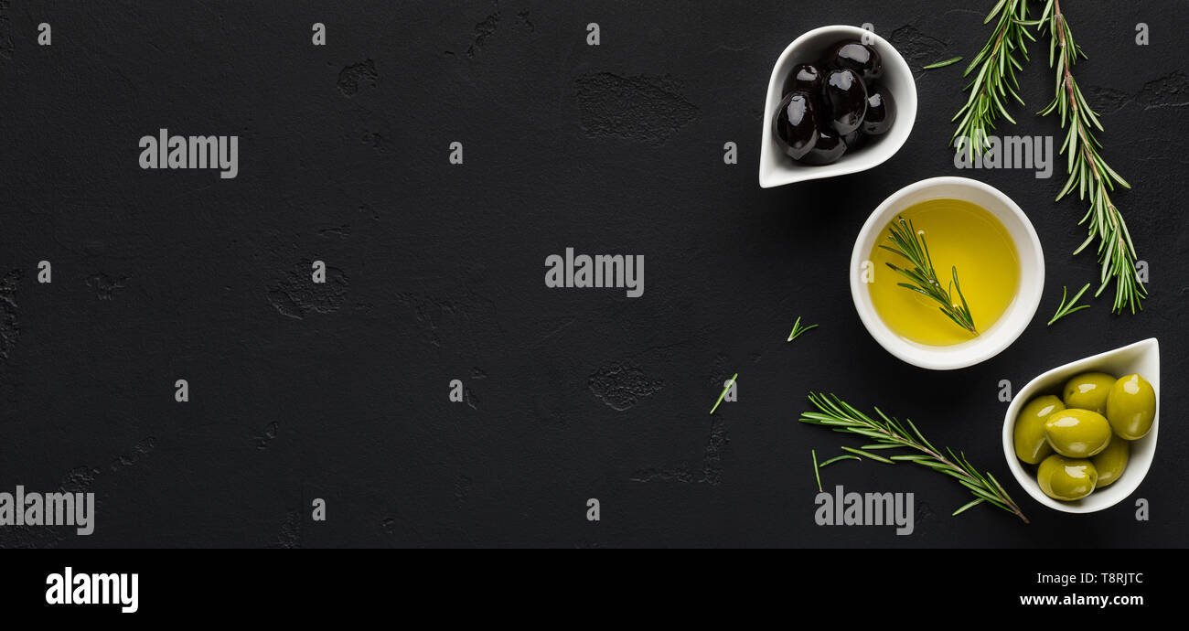 Olivenöl, Rosmarin und Oliven auf Schwarz. Stockfoto