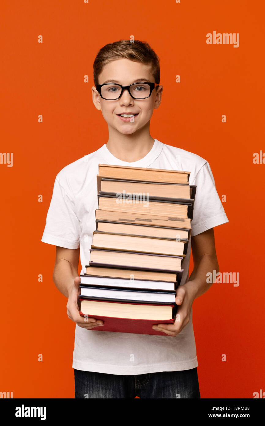 Nette fleißige Schüler Junge in Gläser mit Haufen Bücher Stockfoto