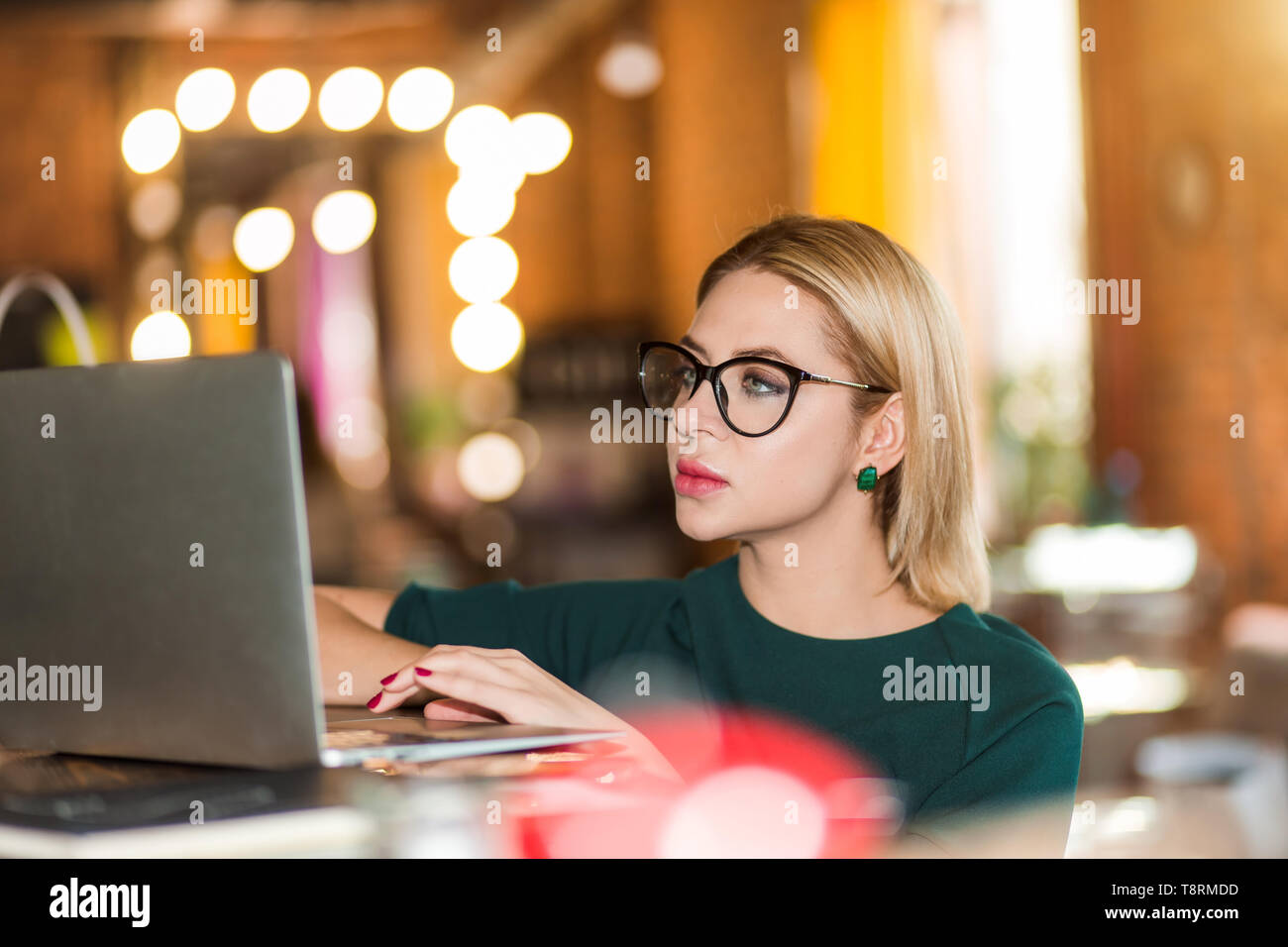 Indoor Nahaufnahme Portrait von attraktiven Blondine konzentriert Freelancer, Administrator, Manager in große Gläser mit Laptop Computer. Selektive konzentrieren. B Stockfoto
