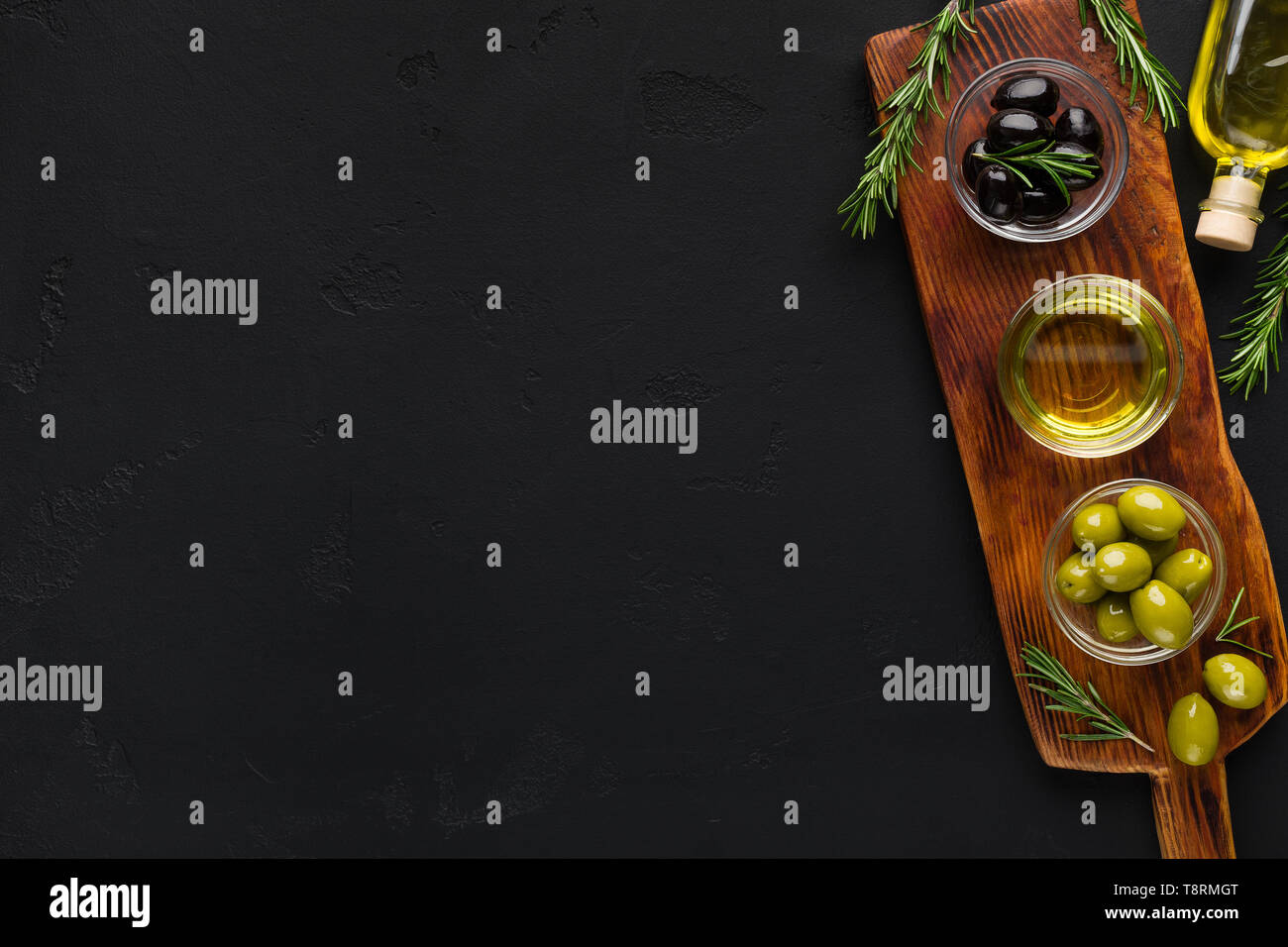 Olivenöl und Oliven in Schalen auf Schwarz. Stockfoto