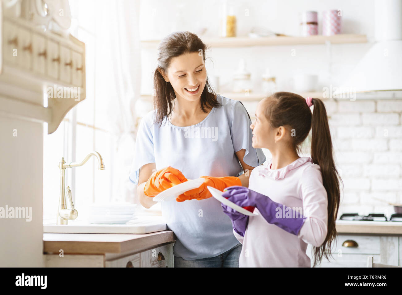 Helfende Hand. Nettes junges Mädchen ihrer Mutter helfen, den Abwasch in der Küche Stockfoto