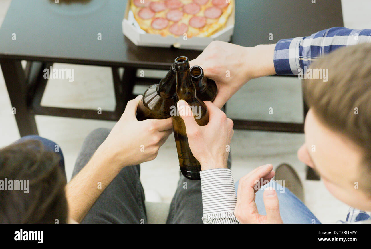 Home Party. Freunde Toasten Bierflaschen, Hohe Betrachtungswinkel Stockfoto
