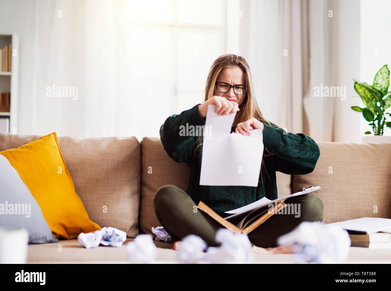 Eine unglücklich, traurig und frustriert weiblichen Kursteilnehmer sitzen auf einem Sofa, reißt das Papier beim Studieren. Stockfoto