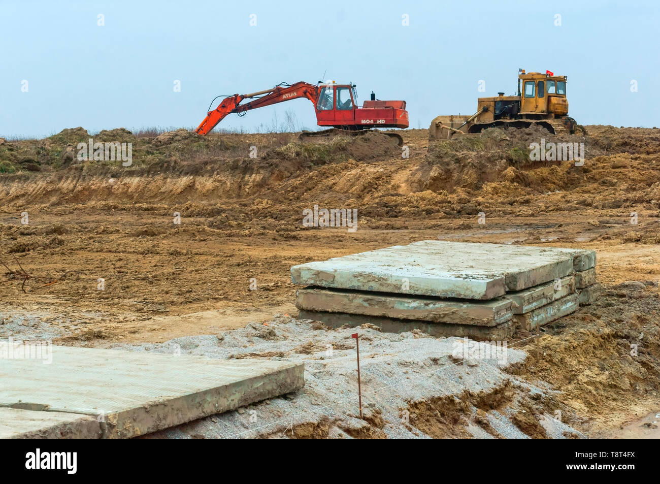 Baumaschinen im Bereich, Betonplatten auf dem Boden und Bagger, der Region Kaliningrad, Russland, 3. März 2019 Stockfoto