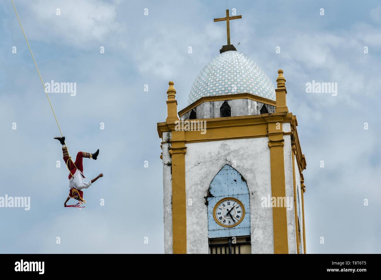 Ein volador führt vor der Kirche Mariä Himmelfahrt in Papantla, Veracruz, Mexiko. Die Danza de los Voladores ist eine indigene Totonac Zeremonie mit fünf Teilnehmern, ein 30-meter Mast klettern. Vier dieser Riegel Seile an ihren Hüften und Wind das andere Ende um die Spitze der Pole, um auf den Boden hinunter. Der fünfte Teilnehmer bleibt an der Spitze der Pole, Spielen, Flöte und eine kleine Trommel. Die Zeremonie wurde als ein Meisterwerk des mündlichen und immateriellen Erbes der Menschheit von der UNESCO eingeschrieben. Stockfoto