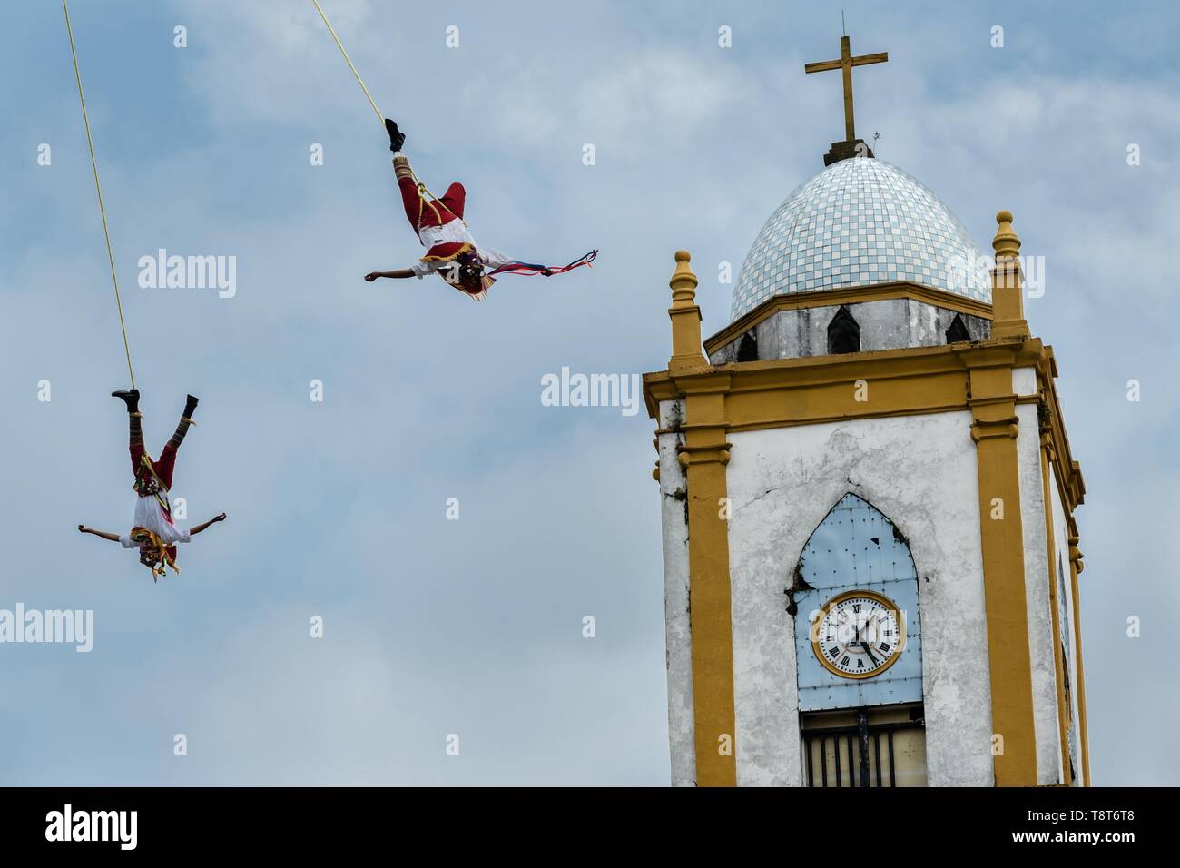 Voladores führt vor der Kirche Mariä Himmelfahrt in Papantla, Veracruz, Mexiko. Die Danza de los Voladores ist eine indigene Totonac Zeremonie mit fünf Teilnehmern, ein 30-meter Mast klettern. Vier dieser Riegel Seile an ihren Hüften und Wind das andere Ende um die Spitze der Pole, um auf den Boden hinunter. Der fünfte Teilnehmer bleibt an der Spitze der Pole, Spielen, Flöte und eine kleine Trommel. Die Zeremonie wurde als ein Meisterwerk des mündlichen und immateriellen Erbes der Menschheit von der UNESCO eingeschrieben. Stockfoto