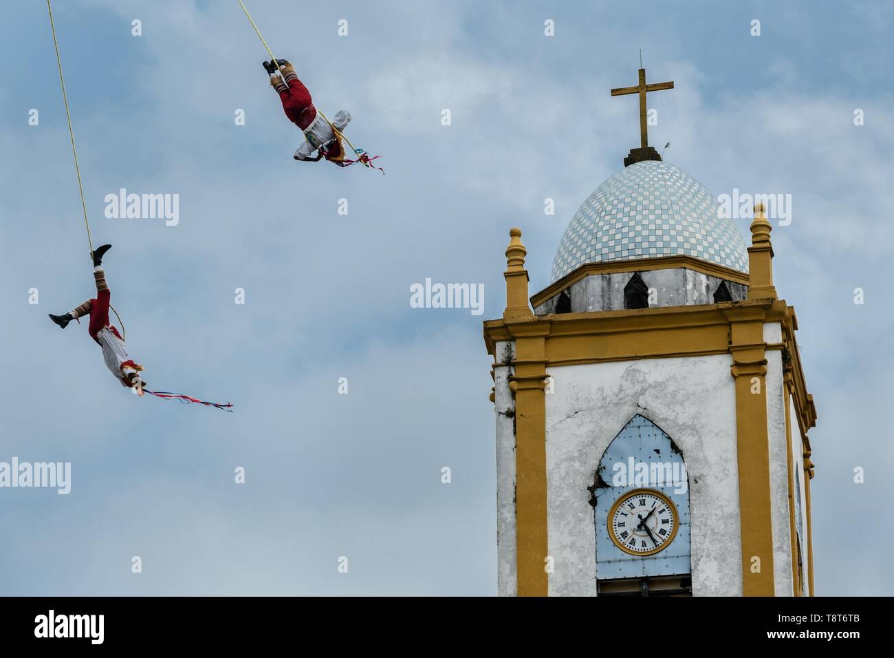 Voladores führt vor der Kirche Mariä Himmelfahrt in Papantla, Veracruz, Mexiko. Die Danza de los Voladores ist eine indigene Totonac Zeremonie mit fünf Teilnehmern, ein 30-meter Mast klettern. Vier dieser Riegel Seile an ihren Hüften und Wind das andere Ende um die Spitze der Pole, um auf den Boden hinunter. Der fünfte Teilnehmer bleibt an der Spitze der Pole, Spielen, Flöte und eine kleine Trommel. Die Zeremonie wurde als ein Meisterwerk des mündlichen und immateriellen Erbes der Menschheit von der UNESCO eingeschrieben. Stockfoto