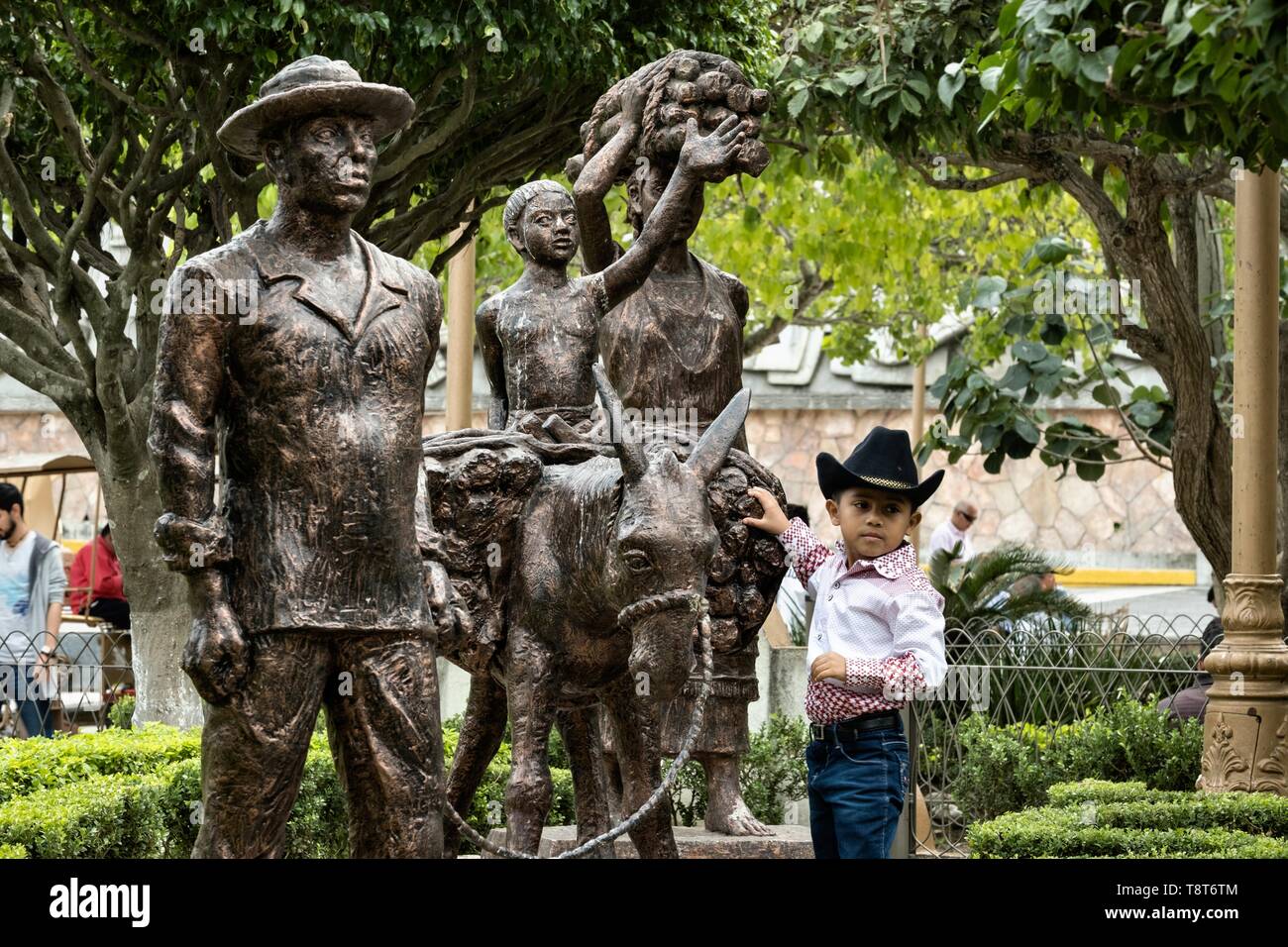 Einem jungen mexikanischen Jungen stellt durch eine Statue zu Ehren des indigenen Totonac Menschen auf der Plaza Central Israel Tellez Park in Papantla, Veracruz, Mexiko. Stockfoto