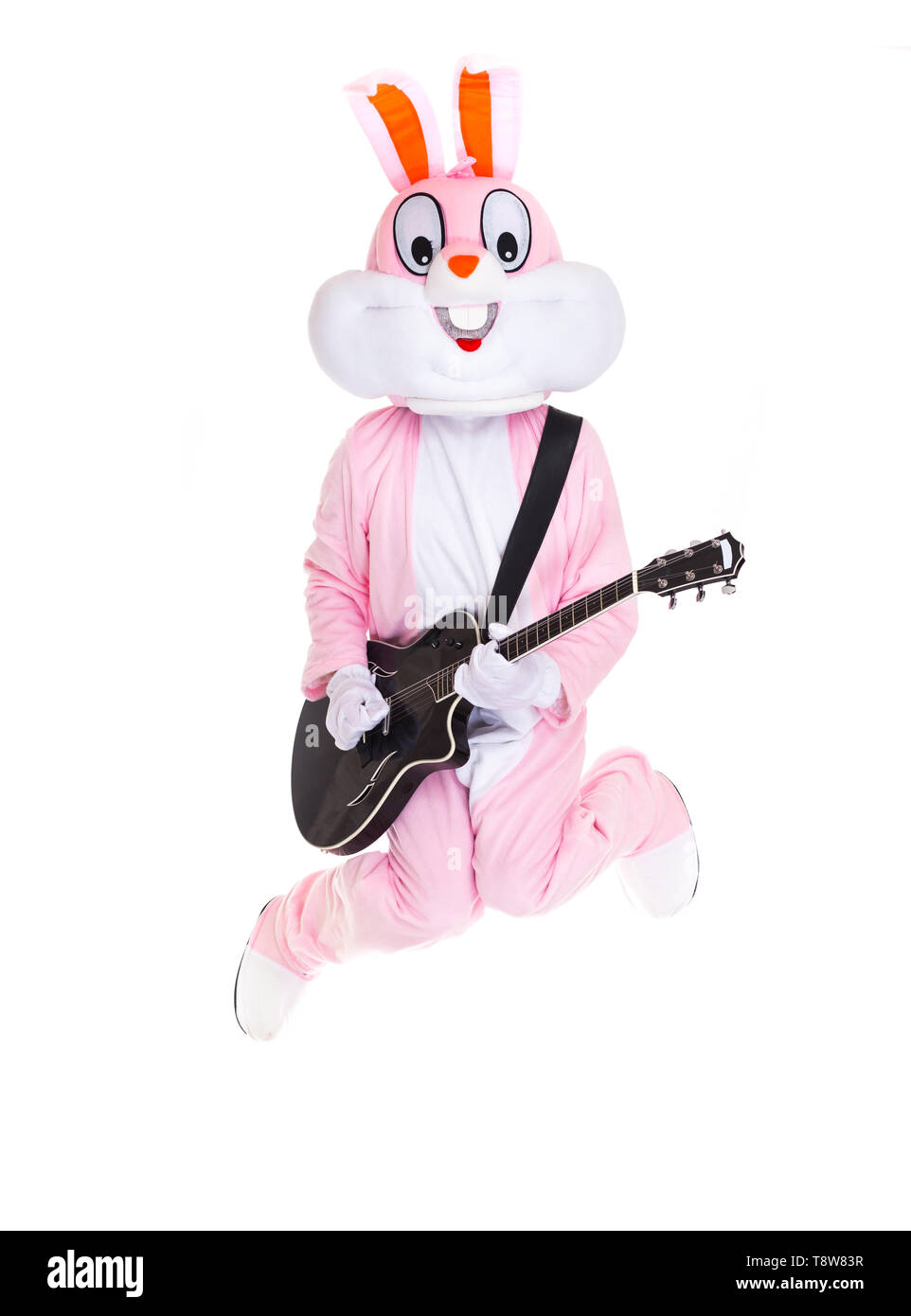 Mann in einem Osterhase Kostüm spielt Musik auf der Gitarre, springt, haben Spaß auf weißem Hintergrund. Lustige Hase oder Kaninchen Gitarrist Lächeln, Spielen von Rock Stockfoto