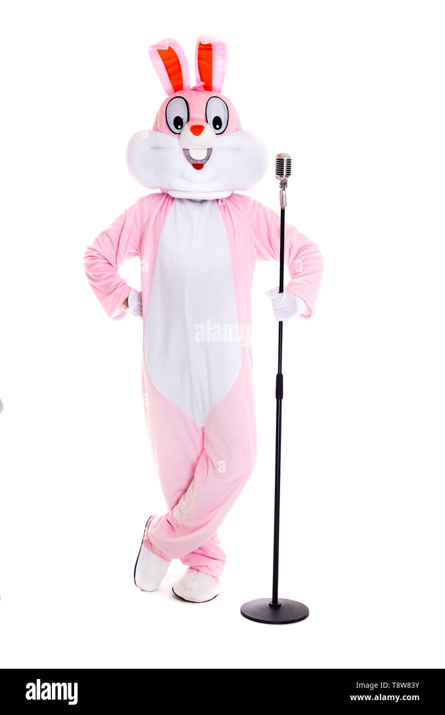 Mann in einem Osterhase Kostüm mit retro Mikrofon, singt, haben Spaß auf weißem Hintergrund. Lustige Hase oder Kaninchen Sänger lächeln Stockfoto