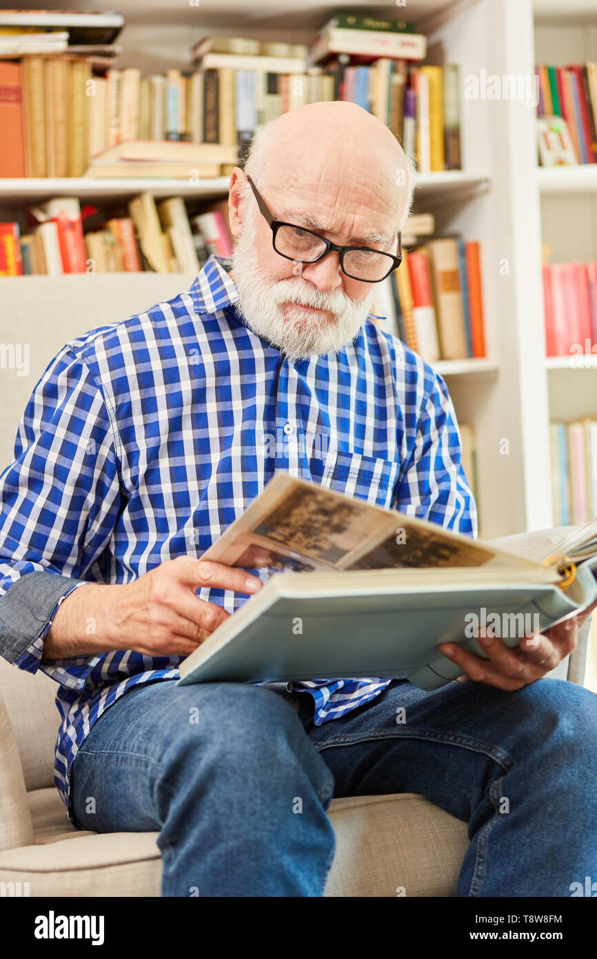 Senior mit Alzheimer sieht auf Fotos im Fotoalbum in betreutes Wohnen Stockfoto