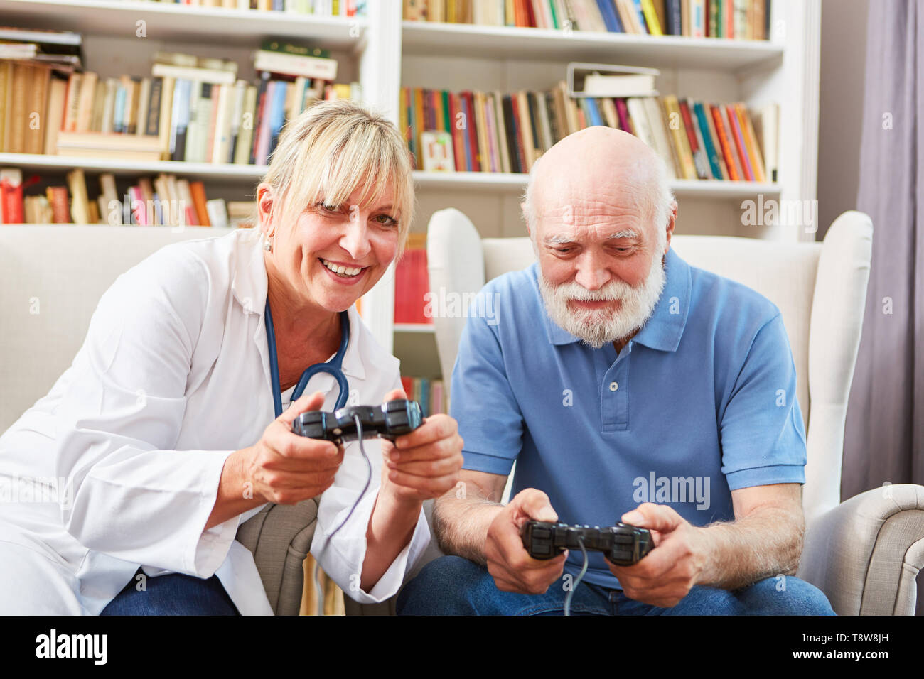 Ärztin und älterer Mann spielen video game in Zusammen betreutes Wohnen Stockfoto