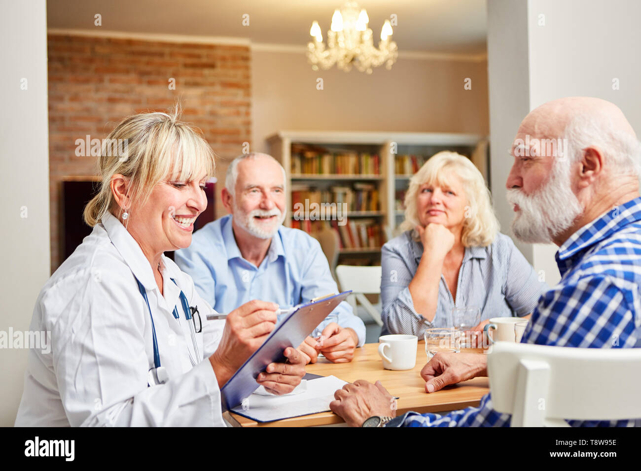 Frau Doktor mit Zwischenablage gemeinsam mit Senioren in einer Gruppe Therapie Sitzung Stockfoto