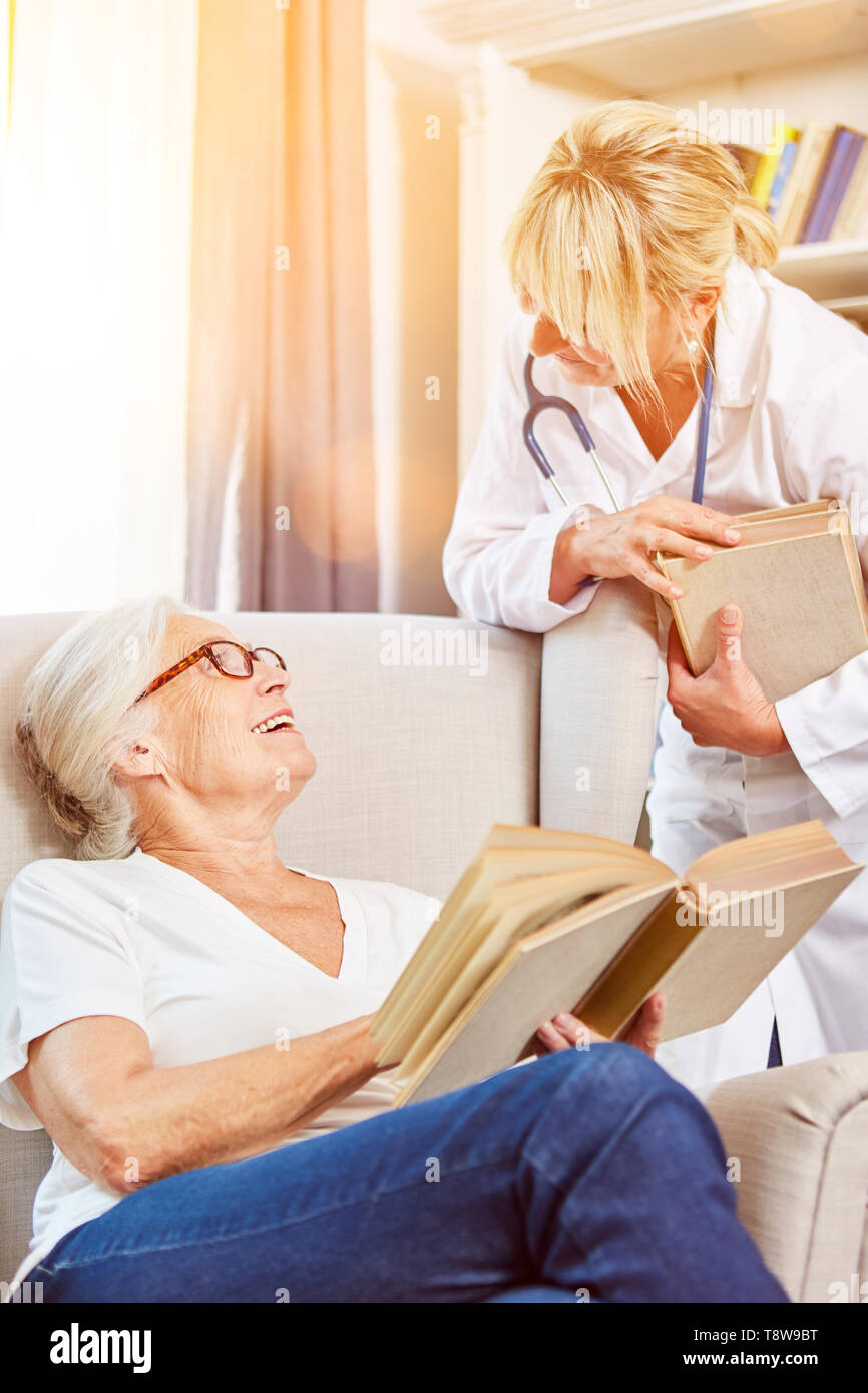 Senior mit Buch spricht zu einem Arzt in der Bibliothek von einem Pflegeheim Stockfoto