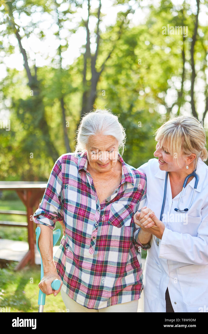 Pflegeperson Hilfen ältere Frau mit krücke im laufenden Ausbildung in der Bewegungstherapie Stockfoto