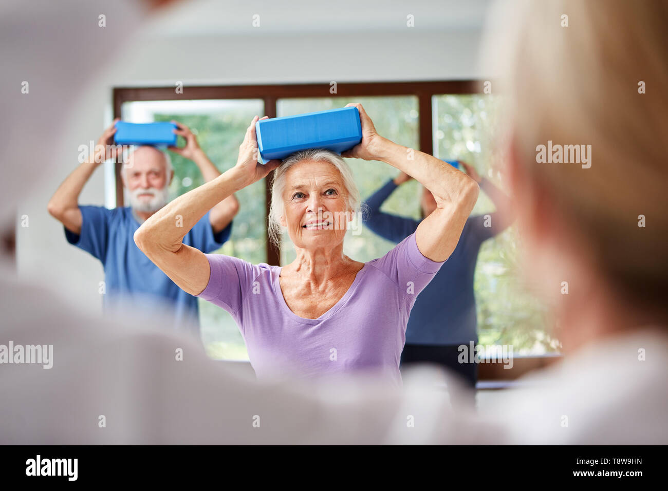 Senioren haben ein Gleichgewicht Übung mit dem Yoga Block wie Rückentraining Stockfoto