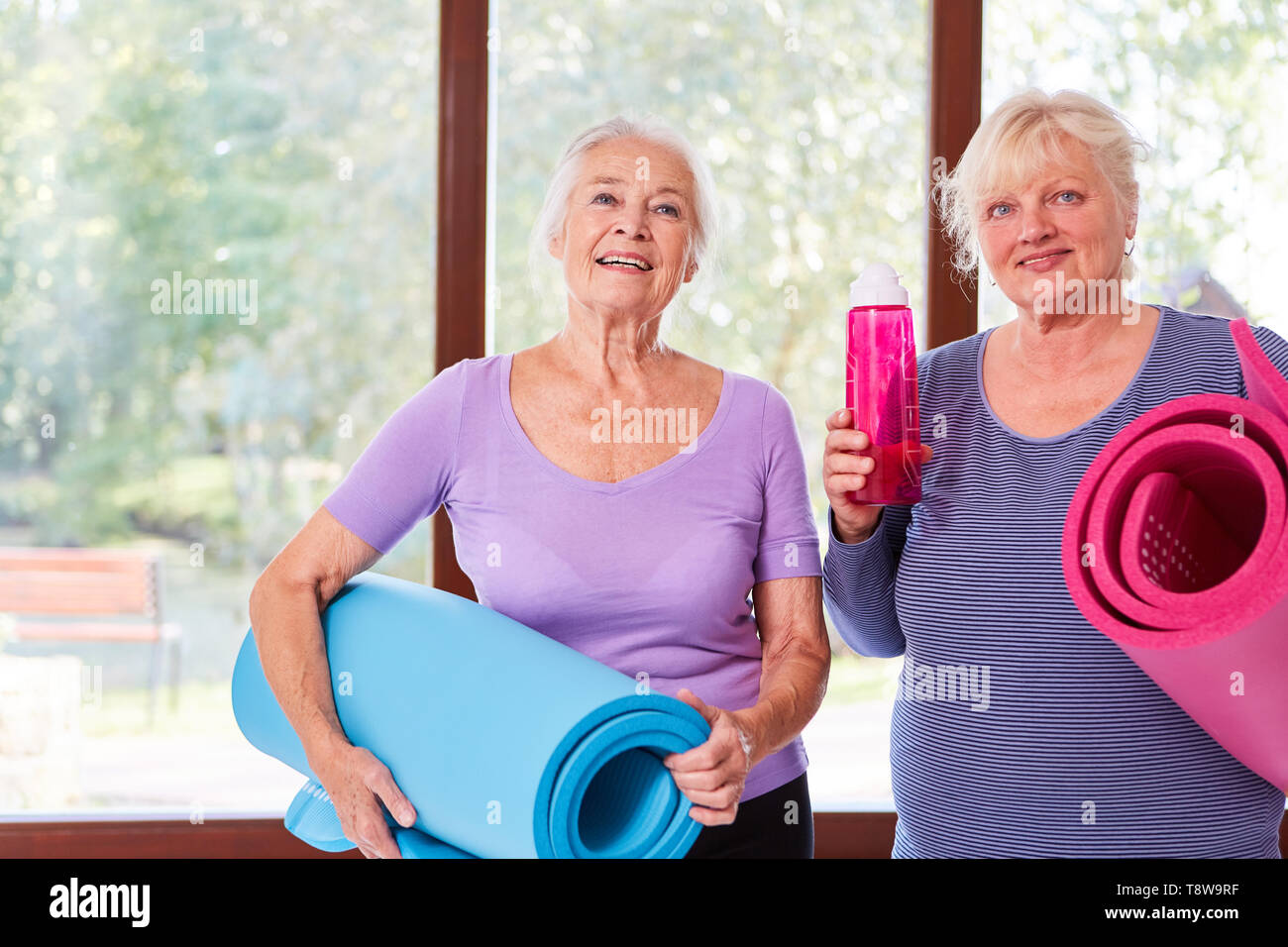 Zwei wesentliche älterer Frauen mit Yoga Matte yoga Klasse im Fitnesscenter Stockfoto