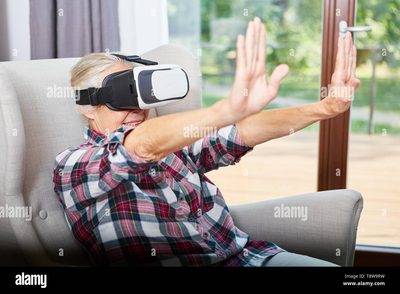 Ältere Frau mit VR-Brille, während Sie mit den Händen im Cyberspace Stockfoto