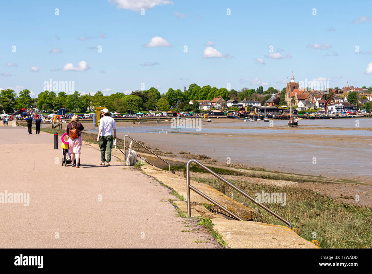 Menschen zu Fuß auf die Promenade an der Maldon, Essex, Großbritannien entlang des Flusses Blackwater. Maldon Stadt im Hintergrund, Kirche, Thames sailing Lastkähne Stockfoto