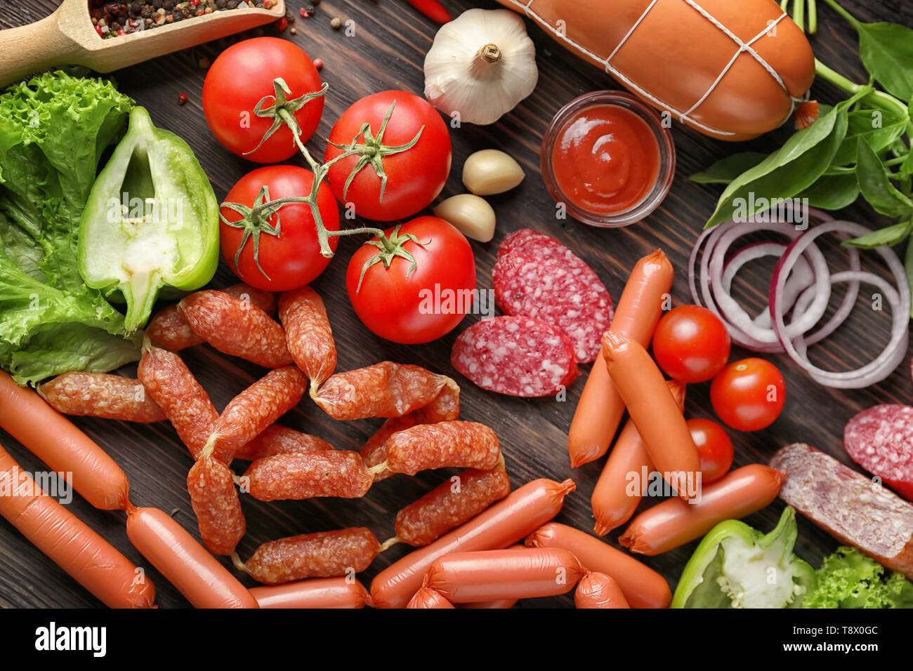 Verschiedene Arten von Würstchen mit Soße und Gemüse auf Holz- Hintergrund Stockfoto