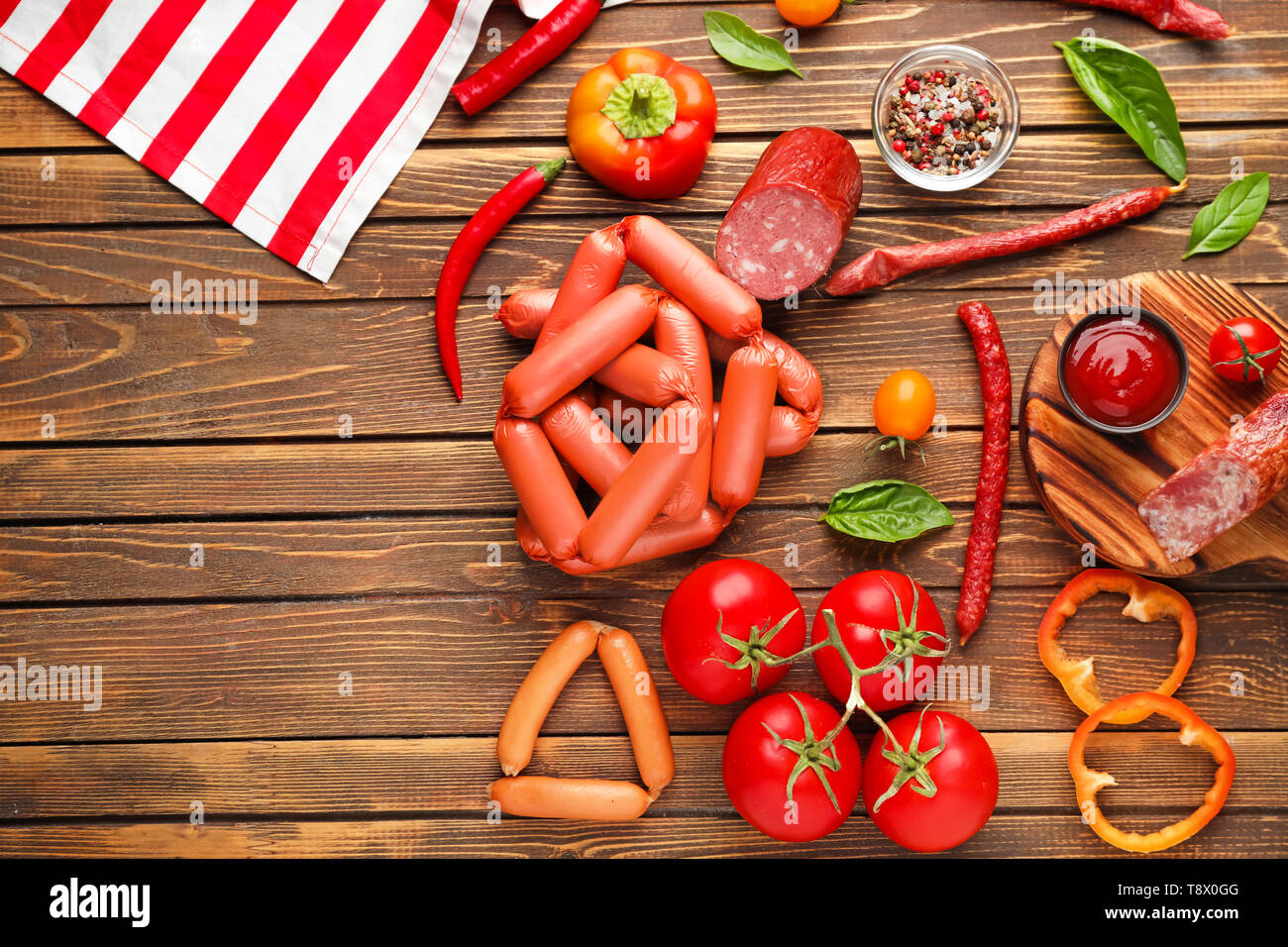 Verschiedene Arten von Würstchen mit Soße und Gemüse auf hölzernen Tisch Stockfoto