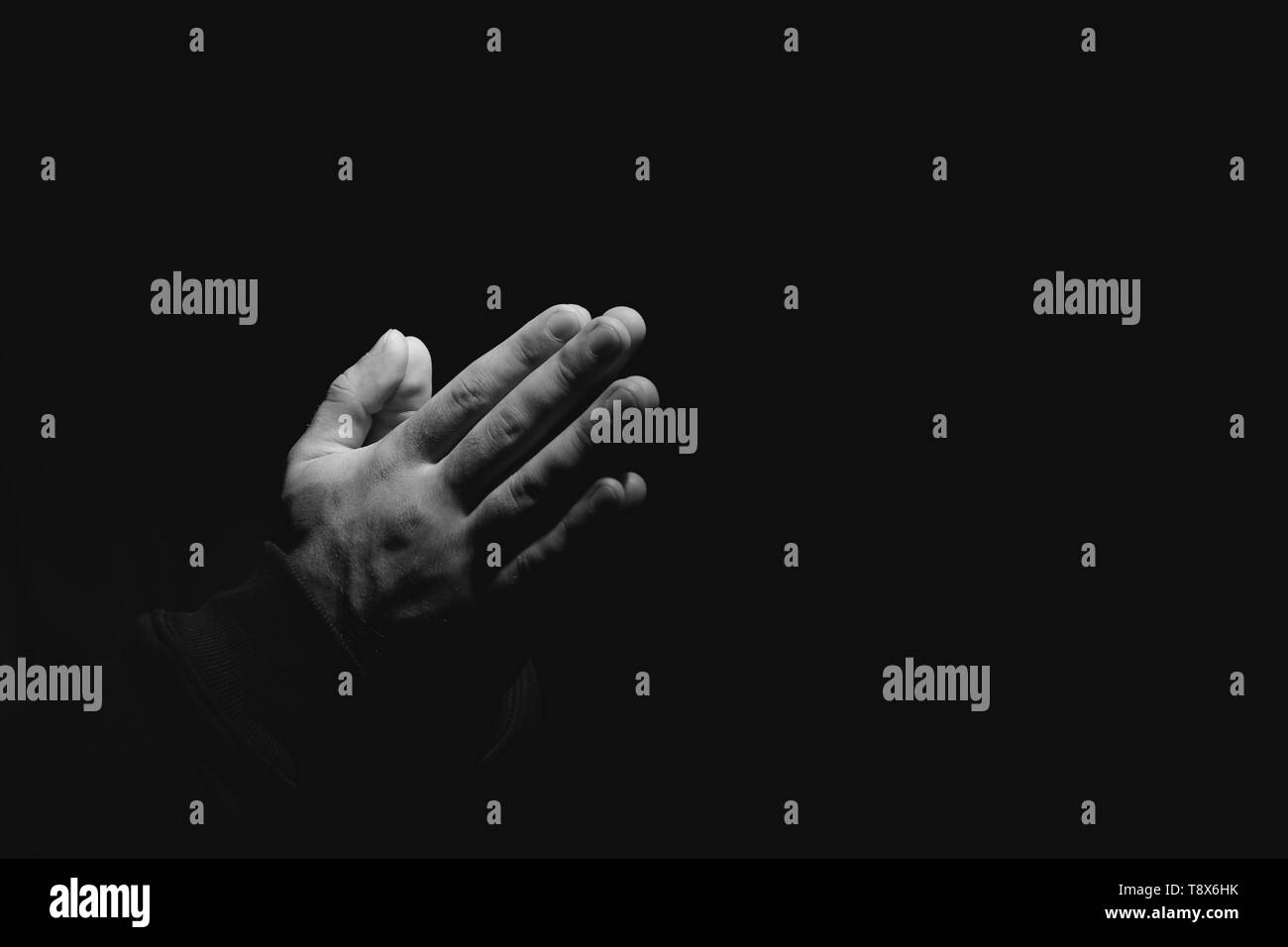 Hände religiöser Mann, der betet auf dunklem Hintergrund, schwarze und weiße Wirkung Stockfoto