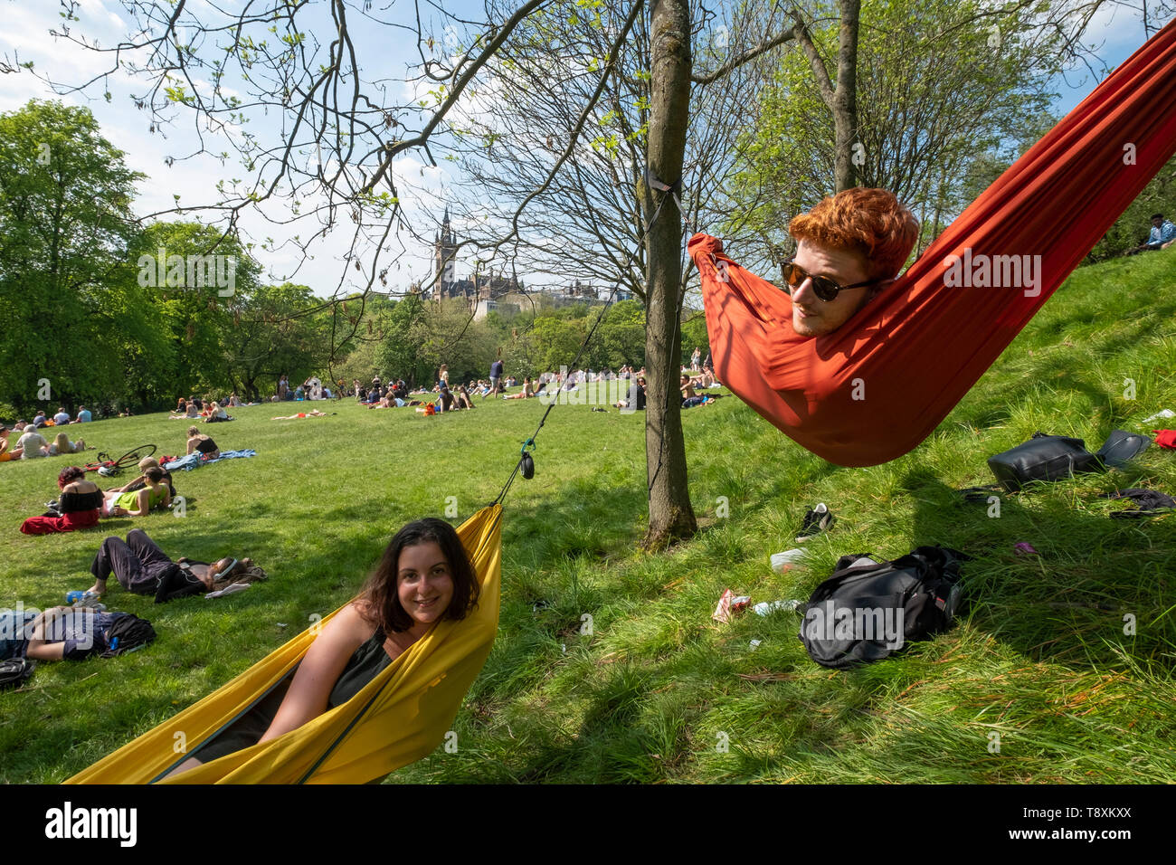 Glasgow, Schottland, Großbritannien. 15 Mai, 2019. Warme, sonnige Wetter in die Stadt brachte Hunderte von jungen Sonnenhungrige zu Kelvingrove Park in der Stadt West End. Bild Miriam und Dom genießen Sie Hängematten an Bäumen im Park. Credit: Iain Masterton/Alamy leben Nachrichten Stockfoto