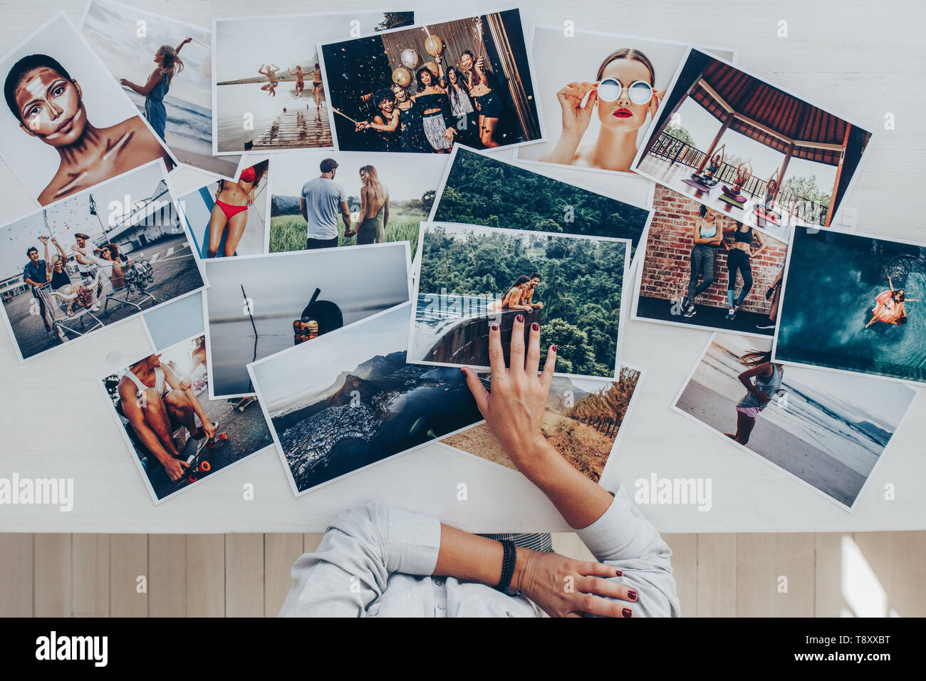 Blick von oben auf einen Fotografen Auswahl der besten Fotos aus mehreren Foto schießen. Fotografin arbeiten im Studio mit Blick auf die Ausdrucke liegen auf dem Schreibtisch. Stockfoto