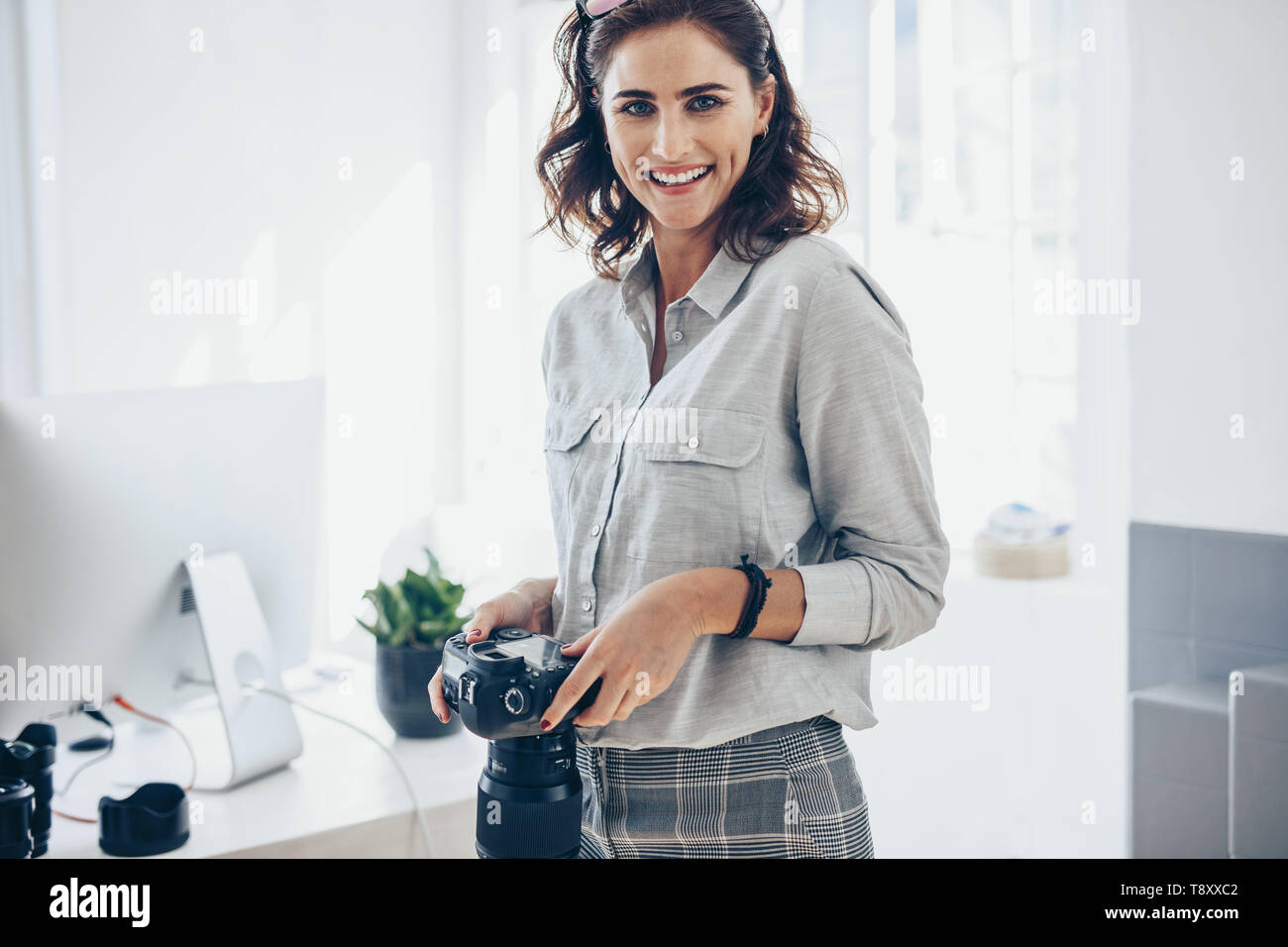 Zuversichtlich Fotografin mit einer professionellen Kamera. Frau mit DSLR-Kamera im Amt. Stockfoto