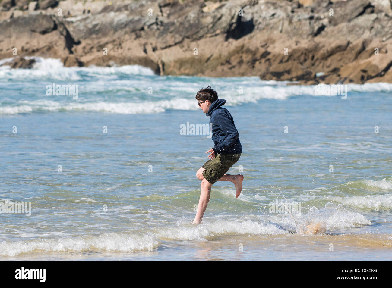 Ein aufgeregter Teenager Urlauber ins Meer laufen auf den Fistral in Newquay in Cornwall. Stockfoto