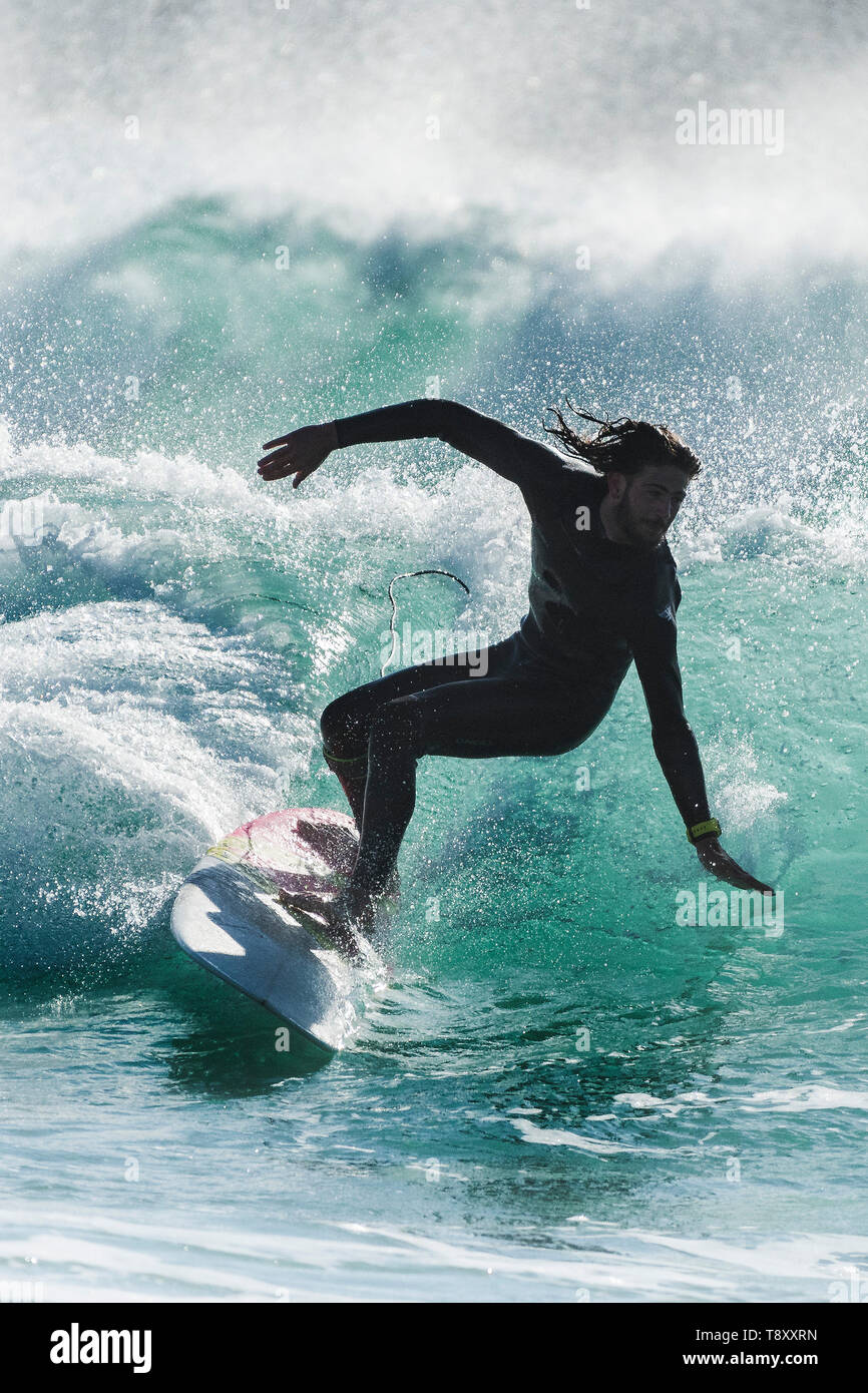 Dramatische surfen Aktion als Surfer ist gegen das Sonnenlicht als reitet eine Welle im Jade farbigen Meer bei Fistral in Newquay in Cornwall. Stockfoto