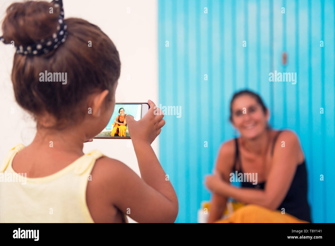 Kleines Mädchen Fotos, die mit dem Smart Phone zu ihrer Mutter vor einem blauen Tür, Ein-eltern-Familie auf Urlaub, geschiedene Frau genießen mit h Stockfoto