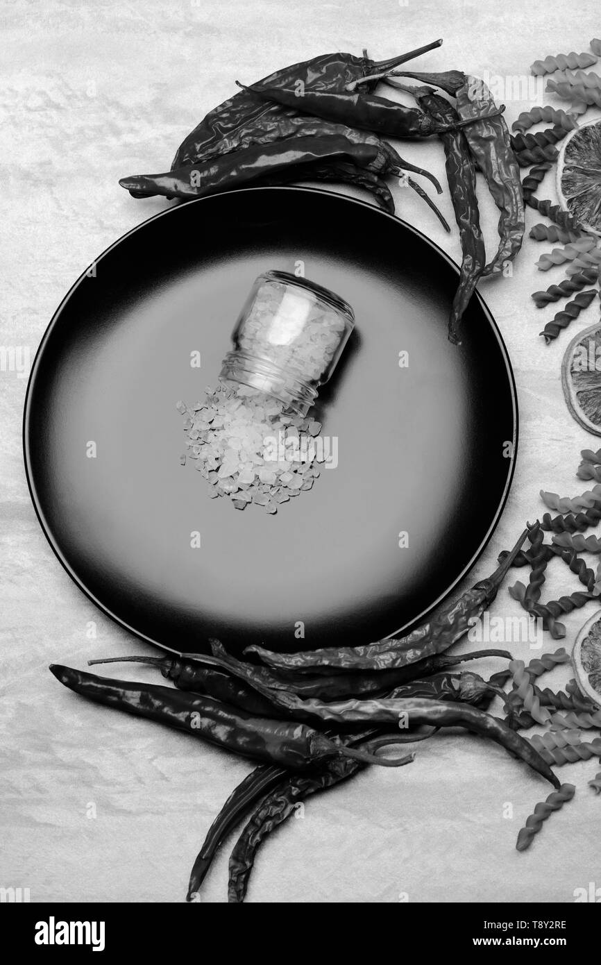 Leckere bunte italienische Pasta, Gewürz im Glas auf Keramikplatte, Chili, Orange, Knoblauch, Stern auf Grau strukturierten Hintergrund Anis, Ansicht von oben Stockfoto