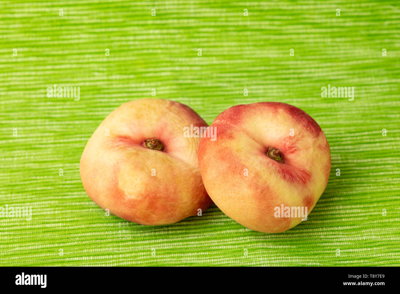 Zwei flache Pfirsiche von oben auf grünem Hintergrund Stockfoto