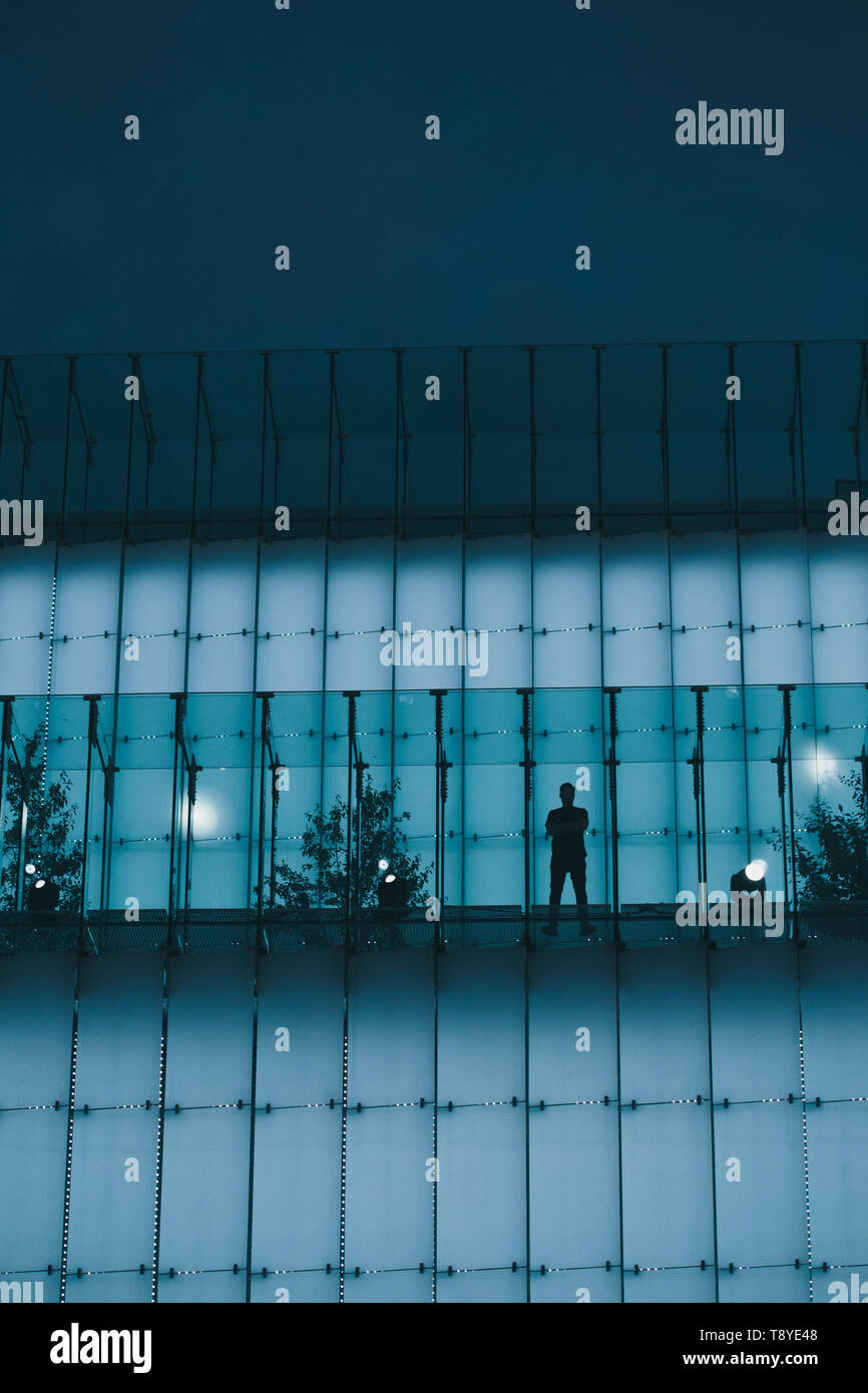 Silhouette der Mann stand auf hinterleuchtetem Glas Bau in der Innenstadt bei Nacht Stockfoto