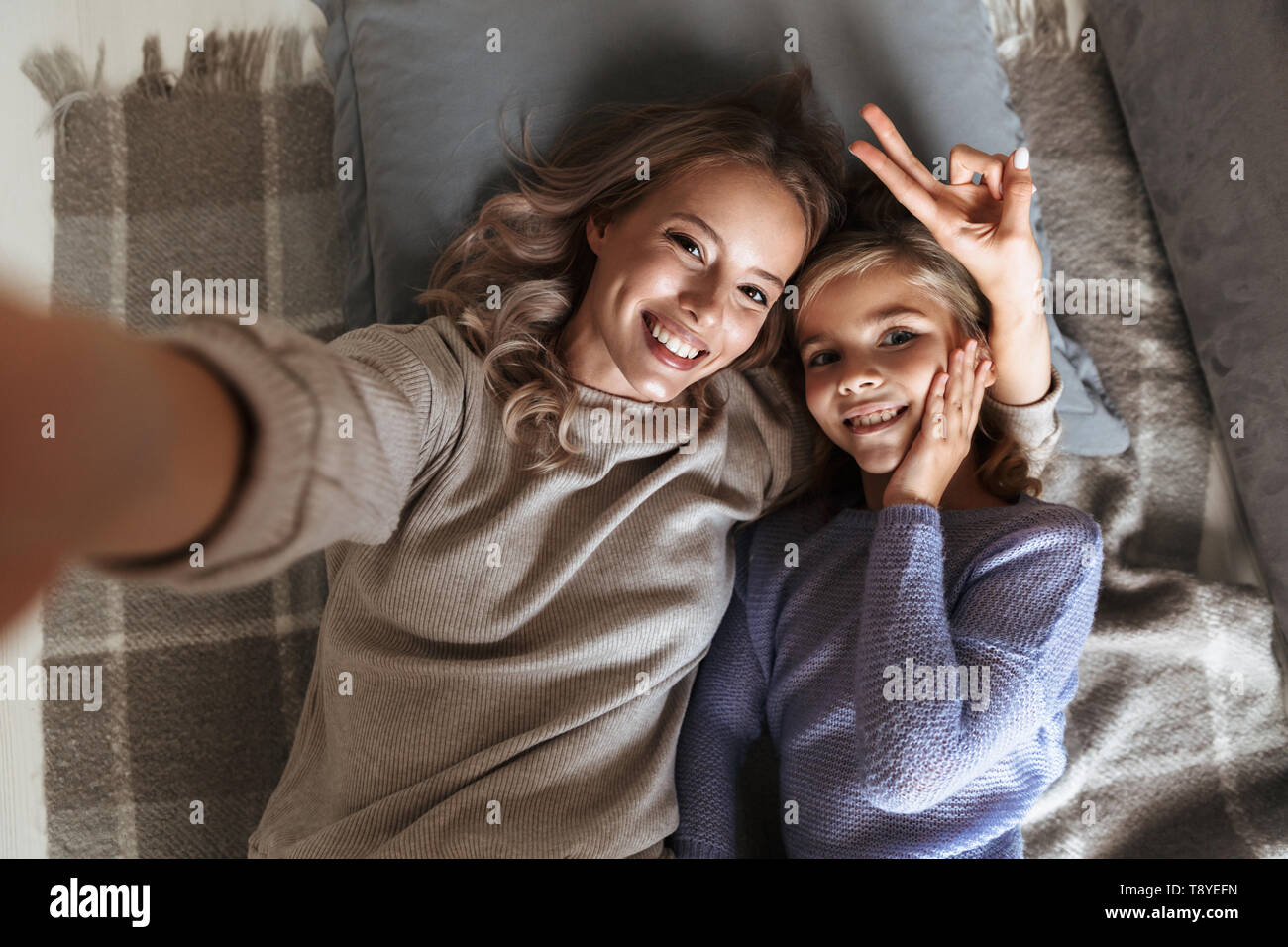 Bild einer glücklichen jungen Frau mit ihrer kleinen Schwester zuhause zu Hause nehmen eine selfie durch die Kamera. Stockfoto